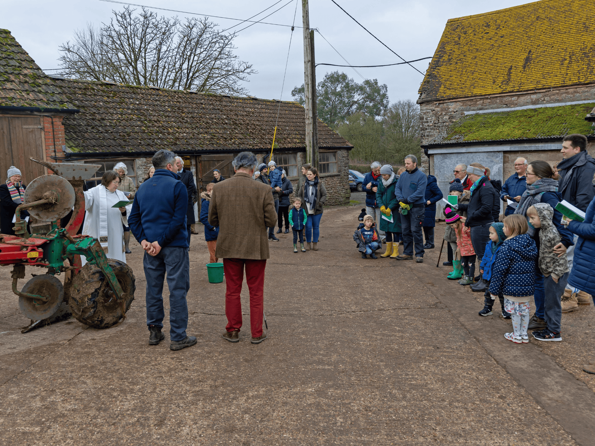 group of male and female farmers and children gathered round a tractor