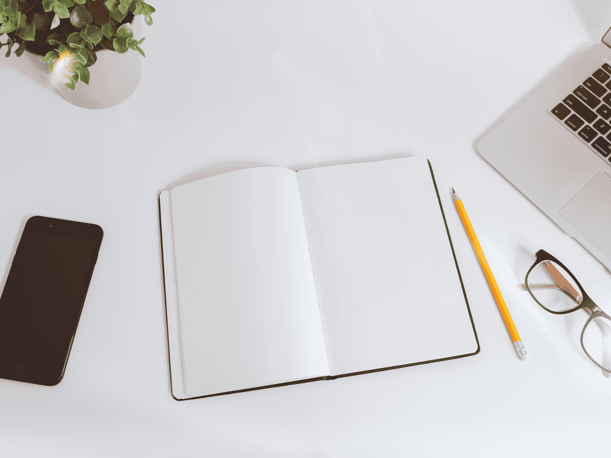 white note pad open with pencil and iphone next to it