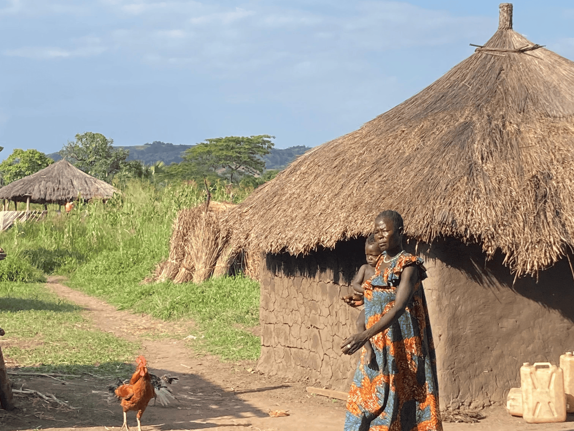 mother and baby in front of mud hut